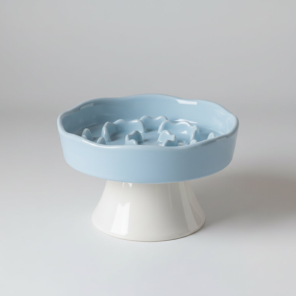 Blue ceramic elevated pet bowl with a slow-feeding surface and an anti-slip base