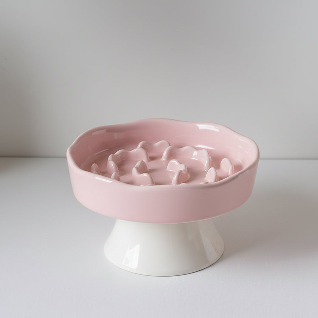 Pink ceramic slow feeder bowl with a raised base that lifts food up off the floor