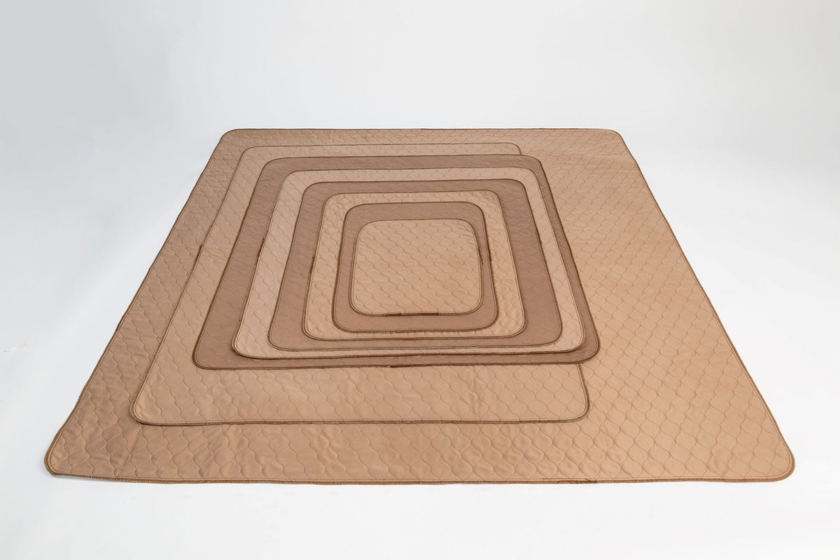 Stack of EZwhelp brown laminated whelping pads with stain-resistant brushed polyester tops